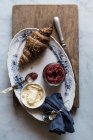 Croissant croccante e marmellata di burro e fragole servita su piatto su tavola di legno — Foto stock