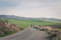 Men riding bicycles on road in desert hills — Foto stock