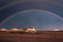 Одинокий старый дом в пустыне и радуга в бурном небе — стоковое фото