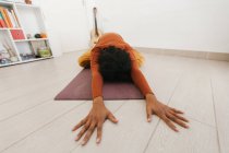 Anonymous woman performing yoga pose and stretching on mat in light room — Stock Photo