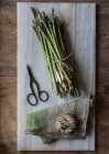 Top view of marble board with pile of asparagus tied with twine rope on wooden table — Stock Photo
