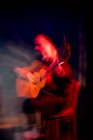 Hispanischer Mann spielt Akustikgitarre bei Flamenco-Auftritt auf dunkler Bühne — Stockfoto