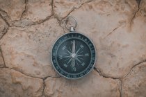 Runder Kompass, der auf brüchigem Wüstenboden nach Norden zeigt — Stockfoto
