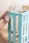 Frauenhände bemalen Holzkiste in blauer Farbe mit Pinsel — Stockfoto