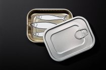 From above example of open tin can isolated on black background with drawings of sardines inside — Stock Photo