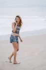 Молода блондинка весела жінка стоїть і говорить по смартфону на морському фоні — стокове фото