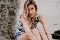 Портрет молодої красивої блондинки спокусливої жінки, що сидить на пляжі і дивиться на камеру — стокове фото