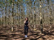 Junge Frau steht im Wald und lächelt — Stockfoto