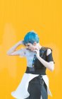 Sensuale giovane donna in abito futuristico alla moda urlando mentre in piedi sul marciapiede contro parete gialla brillante — Foto stock