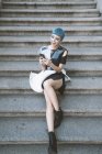 Von oben von einer jungen Frau mit kurzen blauen Haaren und im trendigen futuristischen Kleid mit Telefon auf den Stufen der Straße — Stockfoto