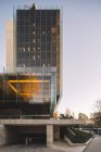 Stilvolles Glashochhaus mit Parkplätzen, die die Sonne bei hellem Tag in der Innenstadt reflektieren — Stockfoto