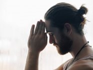 Relaxed thoughtful man in harmony with praying hands in forehead near steamy windows with closed eyes — Stock Photo