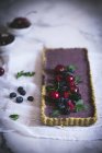 Смачний прямокутний торт, прикрашений літніми ягодами на білому столі — стокове фото