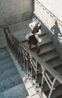Молода жінка з коротким синім волоссям носить модне неформальне плаття і провокативно позує на вуличних сходах — стокове фото