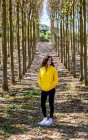 Giovane donna in felpa gialla in piedi nel boschetto e guardando altrove — Foto stock