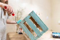Крупный план женщины, рисующей деревянную коробку голубого цвета с роликом — стоковое фото