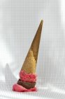 Cône de crème glacée aux fraises et au chocolat tombé sur papier quadrillé — Photo de stock