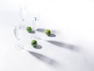 Контрастні тіні зі склянок води та зелених стиглих меблів на білому тлі — стокове фото