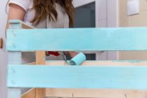Nahaufnahme einer Frau, die Holzkiste in blauer Farbe mit Walze bemalt — Stockfoto