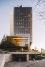 Elegante rascacielos de cristal con aparcamiento que refleja el sol en el día brillante en el centro de la ciudad - foto de stock