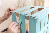 Жіночі руки фарбують дерев'яну коробку синього кольору пензлем — стокове фото