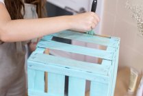 Gros plan de la main femelle douleur boîte en bois de couleur bleue avec pinceau — Photo de stock