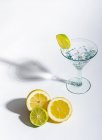 Verre de boisson rempli de glaçons et de tranches d'orange, citron vert et citron sur fond blanc — Photo de stock