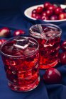 Красный напиток рядом со свежими фруктами на голубой ткани — стоковое фото