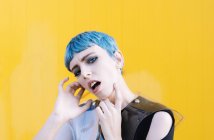 Giovane donna in abito futuristico alla moda sul marciapiede contro parete gialla brillante — Foto stock