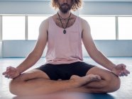 Cropped image of bearded man in sportswear with legs crossed meditating on blue floor with gymnastic balls in studio — Stock Photo