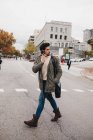 Giovane uomo alla moda che parla sul cellulare mentre cammina sulla strada il giorno d'autunno — Foto stock