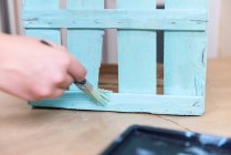 Nahaufnahme einer von Hand bemalten Holzkiste in blauer Farbe mit Pinsel — Stockfoto