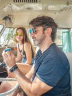 Bearded man and long haired woman in colorful sunglasses sitting in front sea of car and looking at blue little toy car — Stock Photo