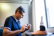Engenheiro protético revisando a prótese de um paciente e melhorando o material em sua oficina — Fotografia de Stock