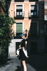 Jovem mulher em vestido futurista de pé com as mãos na cintura na rua contra o velho edifício à luz do sol — Fotografia de Stock