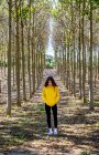 Giovane femmina in felpa gialla in piedi nel boschetto e guardando in basso — Foto stock