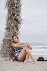 Портрет молодой красивой блондинки соблазнительной женщины, сидящей на пляже и смотрящей в камеру — стоковое фото