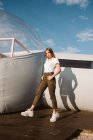 Giovane bella donna in t-shirt bianca, pantaloni e scarpe da ginnastica in posa da glamping trasparente su sfondo cielo blu — Foto stock