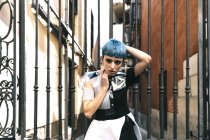 Молода жінка в футуристичній сукні стоїть на вулиці проти старих металевих барів на сонячному світлі — стокове фото