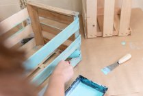 Primer plano de la mujer dolor caja de madera en color azul con rodillo - foto de stock