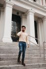 Stylish bearded man standing on stairs, talking on mobile phone outdoors — Stock Photo