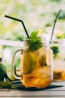 Mojito-Cocktail mit Limette, Minze, Rum, Soda und Eis im Einmachglas auf dem Tisch im Freien — Stockfoto
