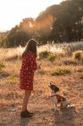 Junge Frau mit langen Haaren spielt mit süßem Hund in der Natur — Stockfoto