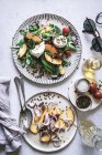 From above plates with gourmet salads made of peaches, red onion, cheese, oil and black pepper on table — Stock Photo