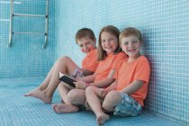 Crianças sentadas em piscina vazia e livro de leitura — Fotografia de Stock