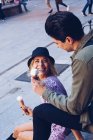 Joyeux jeune femme attrayante et l'homme manger de la crème glacée tout en étant assis à l'extérieur — Photo de stock