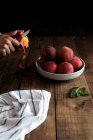 Вкусные спелые персики в тарелке и ручная чистка персика — стоковое фото