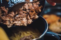 Mano di anonimo che preme carne macinata con forchetta sulla padella durante la cottura in cucina — Foto stock