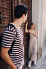 Giovane coppia allegra e giocosa in abiti casual guardando l'un l'altro con amore di fronte alla bella vecchia porta — Foto stock