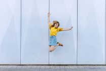 Молодая веселая женщина прыгает в воздухе на голубом фоне — стоковое фото